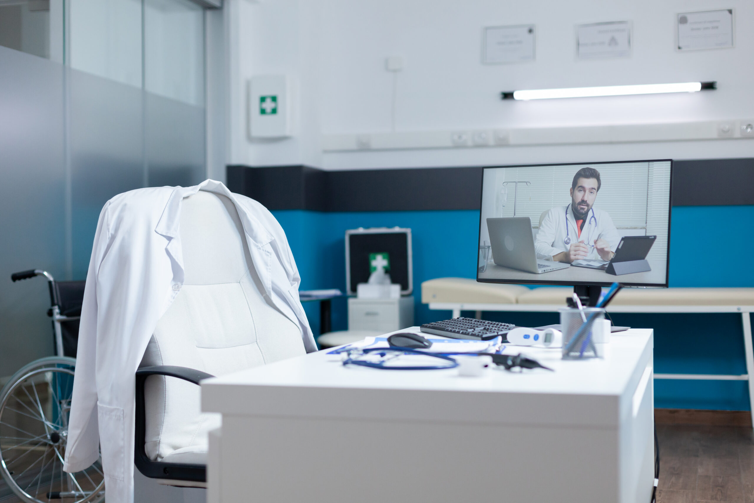 Computer with remote doctor having online telework videocall meeting conference on screen standing on table in empty hospital office. Telemedicine call during medical consultation. Health care service