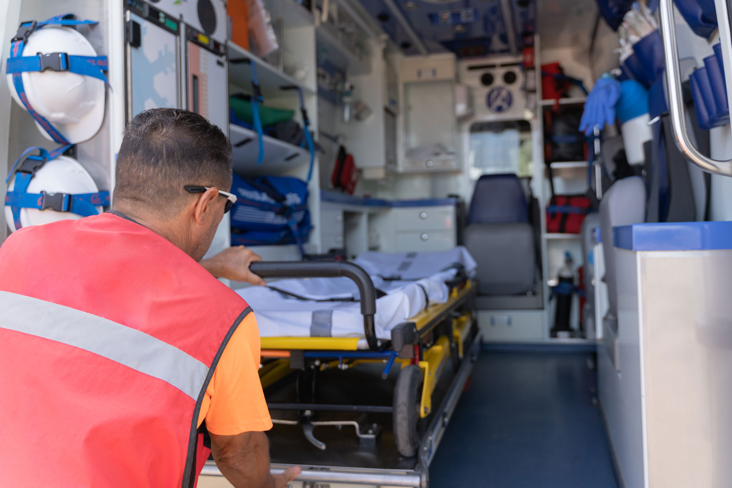 Medical staff taking a stretcher out of an ambulance Rear view of a male member of the medical staff taking a stretcher out of an ambulance